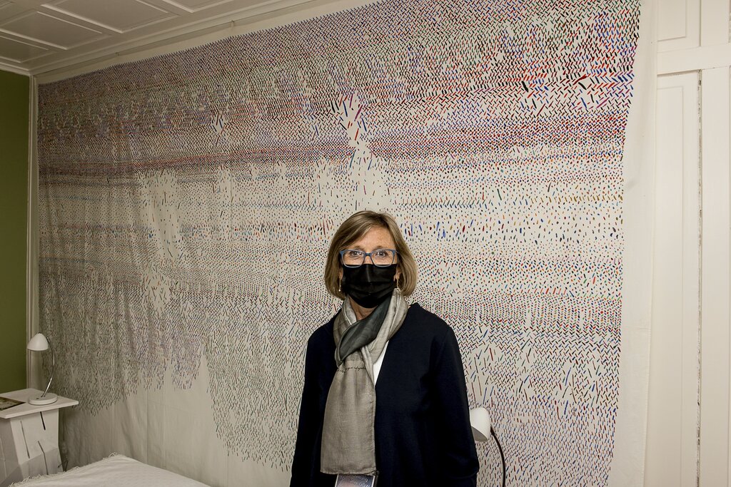 Ana Holenstein-Wyrsch steht im elterlichen Schlafzimmer der Ausstellung vor einem Textilwerk ihrer Mutter Gertrud Guyer Wyrsch.